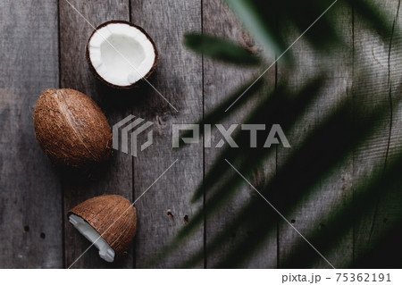 Broken coconuts on gray wooden background with palm leaf. White coconut pulp 75362191