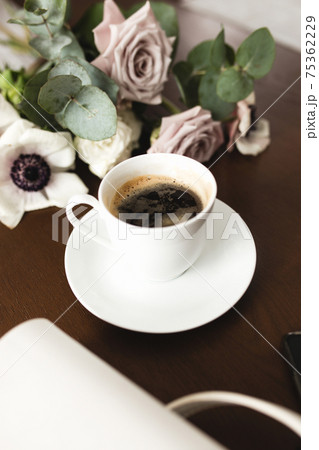 Cup of coffee, bouquet of anemone, purple roses, woman handbag, phone on table Cup of coffee, bouquet of anemone, purple roses, woman handbag, phone on table 75362229