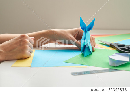 DIY concept. Woman make origami easter rabbit from color paper. Origami lessons DIY concept. Woman make origami easter rabbit from color paper. Origami lessons 75362358