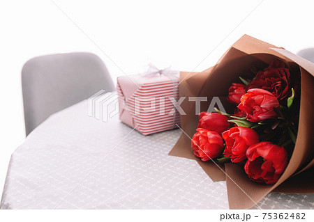 Bouquet of red tulips on table and pink gift box. Concept for greeting card Bouquet of red tulips on table and pink gift box. Concept for greeting card 75362482