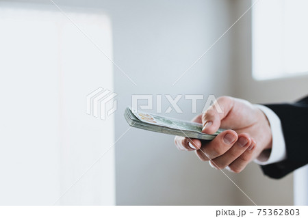 One hundred dollar bills money bundle, in hand of man in suit and white shirt 75362803