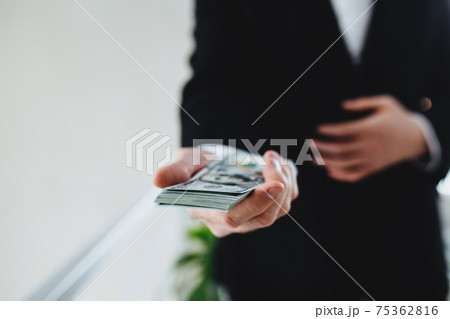 One hundred dollar bills money bundle, in hand of man in suit and white shirt One hundred dollar bills money bundle, in hand of man in suit and white shirt 75362816
