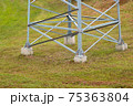 Lower part of a large electric support on a background of green grass 75363804