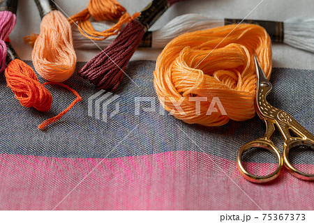 Embroidery equipment on fabric surface -  skeins with floss threads and scissors. Hobbies and recreation, do it yourself concept 75367373