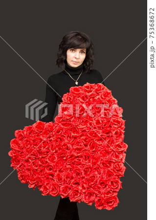 Beautiful brunette with a large bouquet of flowers in the shape of a heart 75368672