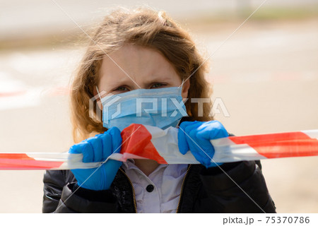 Portrait of sad caucasian child in face mask on closed playground outdoor. Coronavirus social distance quarantine. 75370786