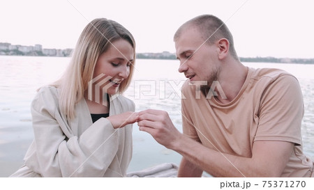 Young man doing proposal to a woman at the lake 75371270