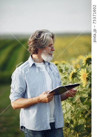 Old farmer in shirt standing on field with notebook 75371602