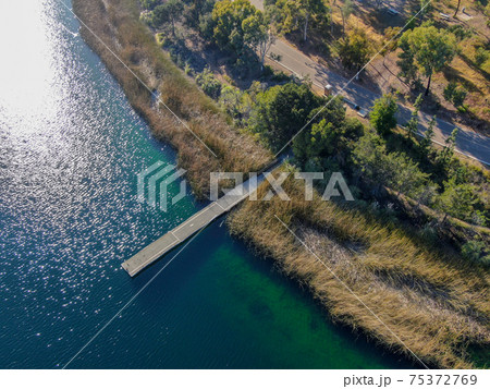 Aerial view of wood pier with fishers and their fishing rods at the Miramar lake, San Diego 75372769