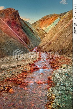 Iconic colorful rainbow volcanic mount Brennisteinsalda (Sulphur Wave) and creek in Landmannalaugar mountain region in Iceland at sunset and blue sky. Iconic colorful rainbow volcanic mount Brennisteinsalda (Sulphur Wave) and creek in Landmannalaugar mountain region in Iceland at sunset and blue sky. 75372777