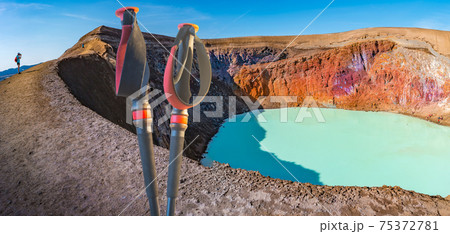 Panoramic view over Icelandic landscape of colorful volcanic caldera Askja, geothermal Viti crater lake in the middle of volcanic desert in Highlands, and hiking poles, Iceland. Panoramic view over Icelandic landscape of colorful volcanic caldera Askja, geothermal Viti crater lake in the middle of volcanic desert in Highlands, and hiking poles, Iceland. 75372781