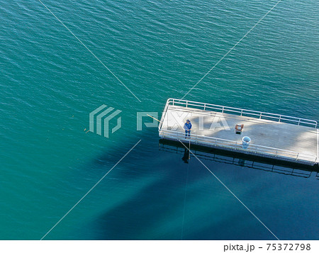 Aerial view of wood pier with fishers and their fishing rods at the Miramar lake, San Diego 75372798