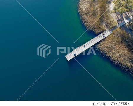 Aerial view of wood pier with fishers and their fishing rods at the Miramar lake, San Diego 75372803
