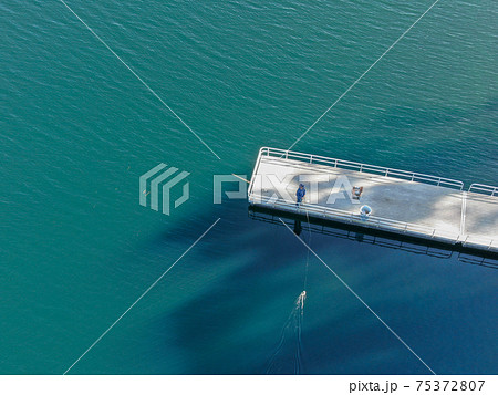 Aerial view of wood pier with fishers and their fishing rods at the Miramar lake, San Diego 75372807