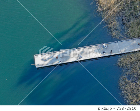 Aerial view of wood pier with fishers and their fishing rods at the Miramar lake, San Diego 75372810