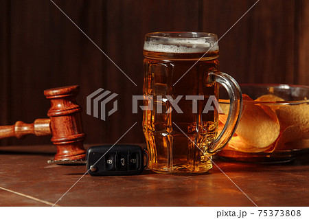 Glass of beer, car keys and wooden judge gavel. Alcohol and car accidents concept Glass of beer, car keys and wooden judge gavel. Alcohol and car accidents concept 75373808