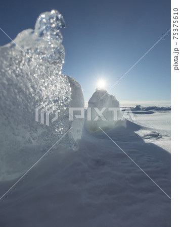 Ice slopes in sunny winter day, transparent ice of blue color, purely blue sky, long shadows, a pure snow-covered virgin soil, snow barkhans,  75375610