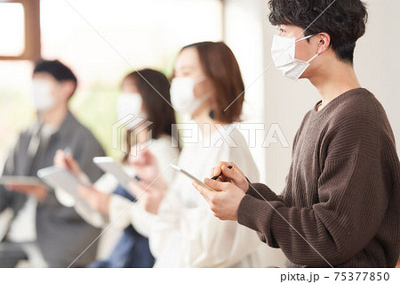 タブレットとタッチペンを使うマスク装着の男性 75377850