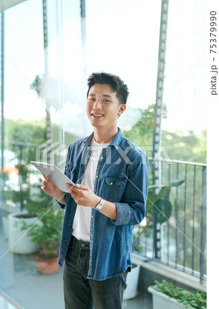 Sunny Day, Man Standing and Browsing on Tablet in Balcony, Gadget 75379990