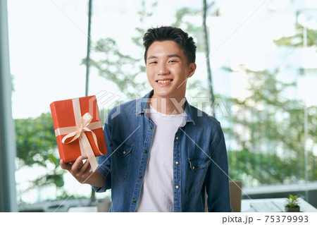 present box with gold ribbons standing on the table in hands 75379993