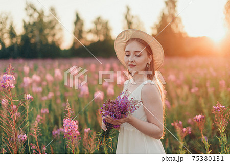 a happy girl with bouquet walks through a flower meadow. Love and spring blooming 75380131