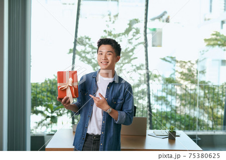 a gift box in hands of young businessman in office a gift box in hands of young businessman in office 75380625