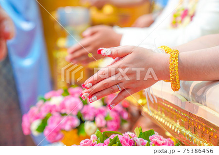 Water pouring ceremony, the closing of the bride's hand that is blessing pouring water using the conch shell. Traditional Thai wedding. Water pouring ceremony, the closing of the bride's hand that is blessing pouring water using the conch shell. Traditional Thai wedding. 75386456