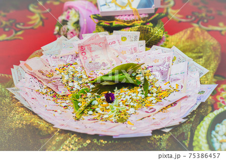 Focusing on the bride's price at a Thai wedding ceremony, cash is placed on the golden tray and sprinkled with flowers. Focusing on the bride's price at a Thai wedding ceremony, cash is placed on the golden tray and sprinkled with flowers. 75386457