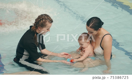 Mother and infant son at swimming lesson with female instructor Mother and infant son at swimming lesson with female instructor 75386725