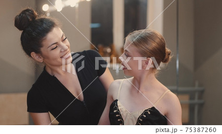 Teacher and young ballerina looking at each other and smiling Teacher and young ballerina looking at each other and smiling 75387260