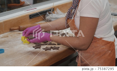 Woman cutting chocolate shortcrust dough for cookies Woman cutting chocolate shortcrust dough for cookies 75387295