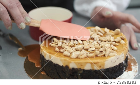 Female pastry chef prepares a cake and decorates it with cashew 75388283