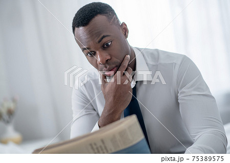 Elegant man sitting and reading a newspaper Elegant man sitting and reading a newspaper 75389575