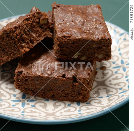 baked square pieces of brownie walnut chocolate cake lie in a round plate 75391726