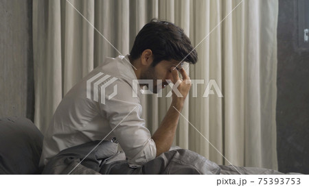 Depressed lonely business middle east man is fired from job. Sitting on bed in bedroom at home in early morning. Quarantine lifestyle. Unhappy life. 75393753