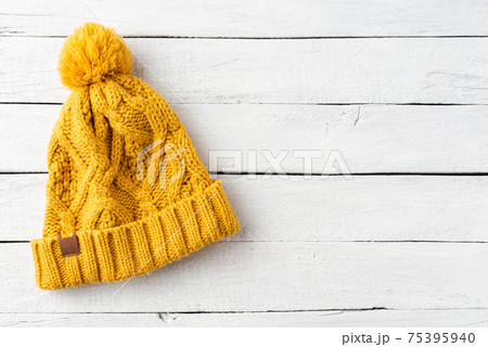 Yellow winter hat with pompon on white wooden background with copyspace. Top view Yellow winter hat with pompon on white wooden background with copyspace. Top view 75395940