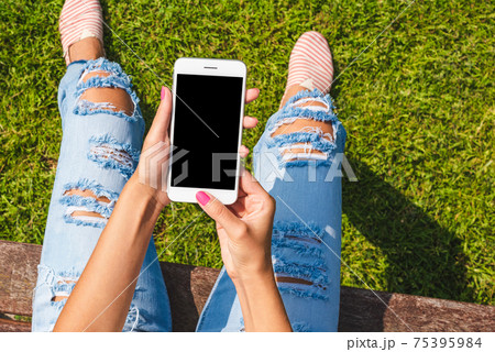 Fashionable young woman holding smartphone with blank screen 75395984