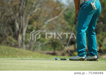 Golfer putting ball on the green golf, lens flare on sun set evening time. Golfer action to win after long putting golf ball in to the hole. Golfer putting ball on the green golf, lens flare on sun set evening time. Golfer action to win after long putting golf ball in to the hole. 75396988