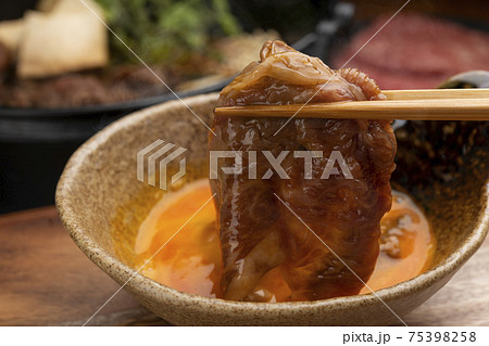 すき焼きの牛肉に生卵をつけて食べる すき焼きの牛肉に生卵をつけて食べる 75398258