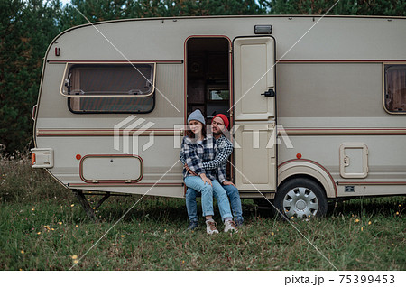 Couple spending time together near trailer home. Traveling with motor home. Couple spending time together near trailer home. Traveling with motor home. 75399453