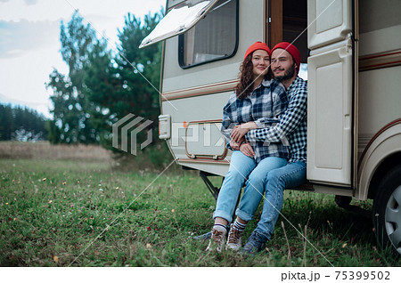 Couple spending time together near trailer home. Traveling with motor home. Couple spending time together near trailer home. Traveling with motor home. 75399502
