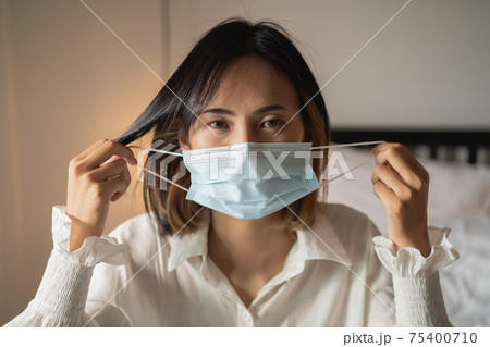 close up women wearing surgical mask in the bedroom 75400710