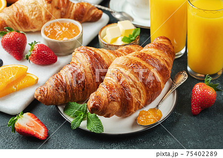 Fresh sweet croissants with butter and orange jam for breakfast. Continental breakfast on a black concrete table. 75402289