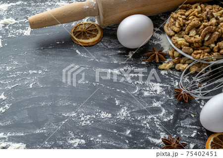 Bakery food. Fresh food ingredients: flour, eggs, nut and star anise, orange on black chalkboard background for bread. Cooking flat lay with copy space. Top view. Baking concept. Bakery food. Fresh food ingredients: flour, eggs, nut and star anise, orange on black chalkboard background for bread. Cooking flat lay with copy space. Top view. Baking concept. 75402451