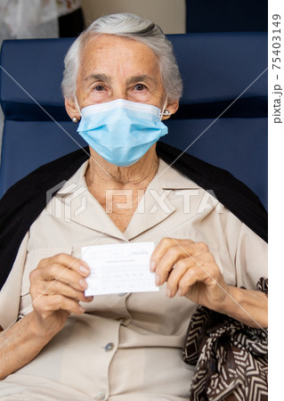 Senior woman holding her vaccination certificate after getting the Covid-19 vaccine at a vaccination site in Colombia. Authentic vaccination. Real patient Senior woman holding her vaccination certificate after getting the Covid-19 vaccine at a vaccination site in Colombia. Authentic vaccination. Real patient 75403149