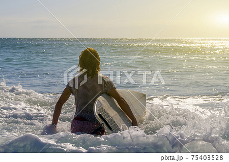 Male surfer entering the sea with his board.Ready for a great surfing day. Male surfer entering the sea with his board.Ready for a great surfing day. 75403528
