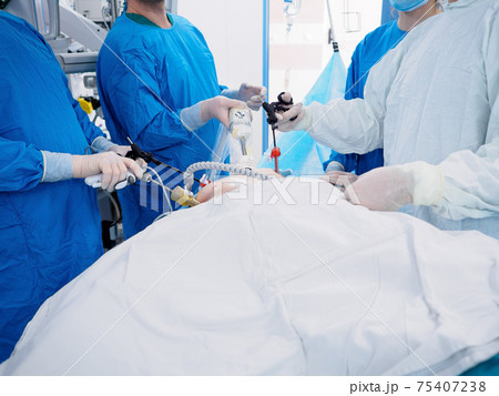 Surgeons in blue uniforms perform laparoscopic surgery using special medical equipment. Surgeons in blue uniforms perform laparoscopic surgery using special medical equipment. 75407238