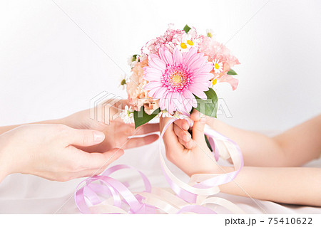 花束を渡す子供の手 花のプレゼントイメージ素材の写真素材