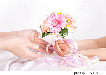 花束を渡す子供の手　花のプレゼントイメージ素材 75410626