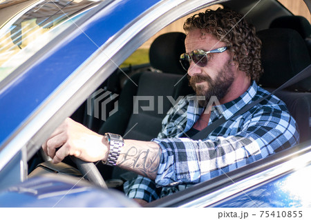 サングラスをかけて青い車に乗っている外国人中年男性の写真素材